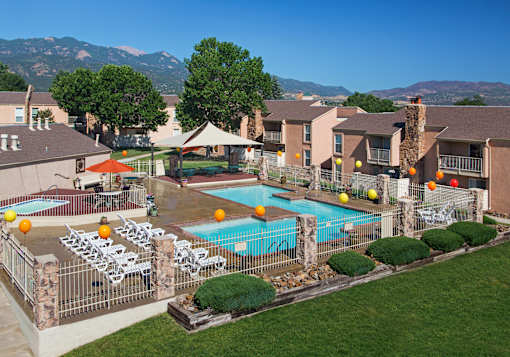 A pool surrounded by chairs and umbrellas with mountains in the background.