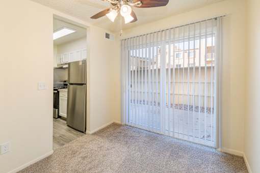 A room with a fan and a sliding door leading to a balcony.