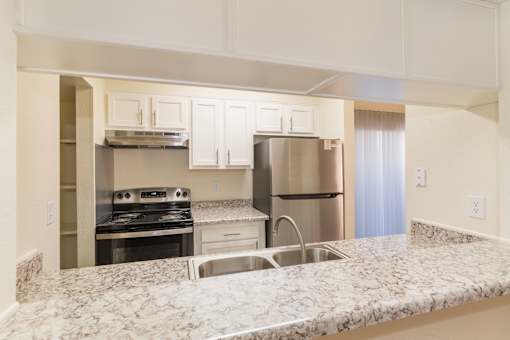 A kitchen with a granite countertop and stainless steel appliances.