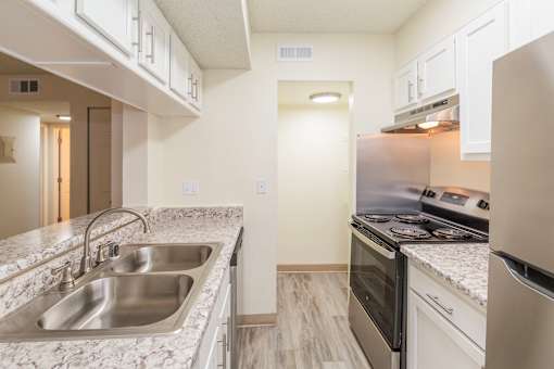 A kitchen with a stainless steel sink and white cabinets.