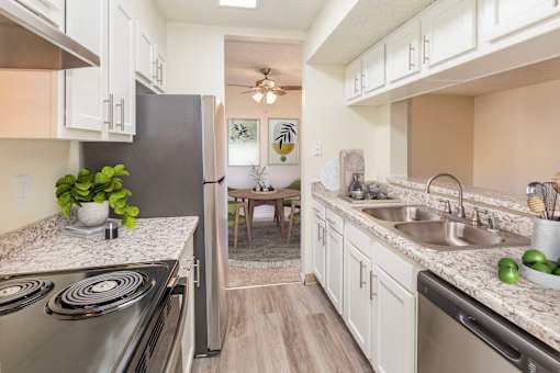 A kitchen with a stove, sink, and refrigerator.