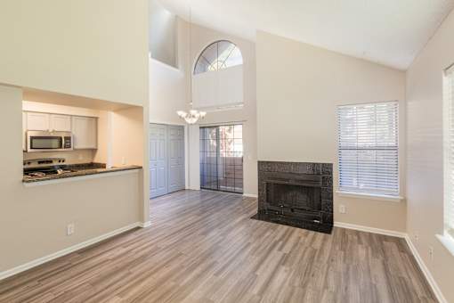A living room with a fireplace and a kitchen area in the background.