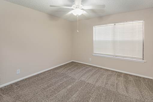 A room with a ceiling fan and a window with blinds.