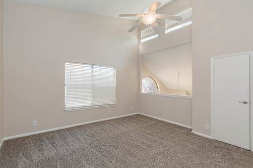 A room with a ceiling fan and carpeted floor.