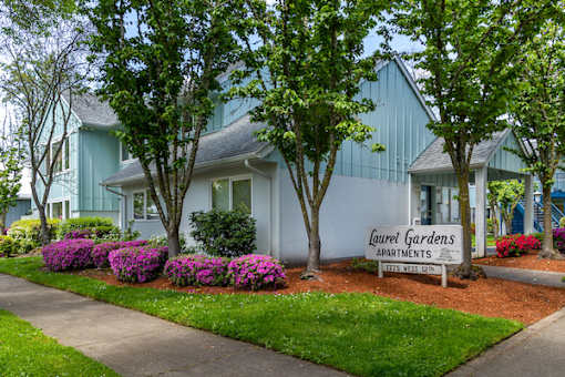 A sign that says "Laurel Gardens Apartments" is in front of a building.