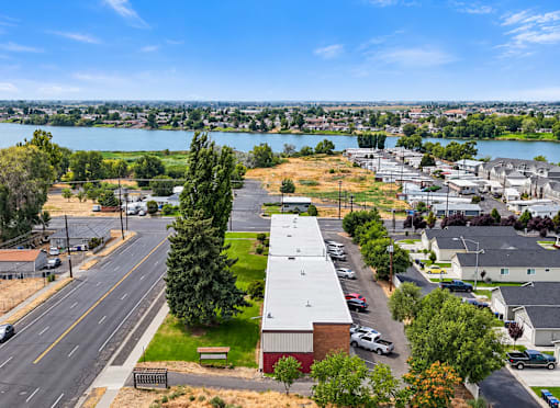 A view of a street with cars and buildings with a lake in the background.