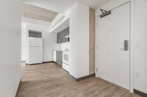 A kitchen with white appliances and wooden floors.