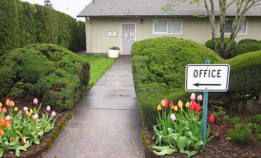 A white sign with the word office on it is in front of a building.