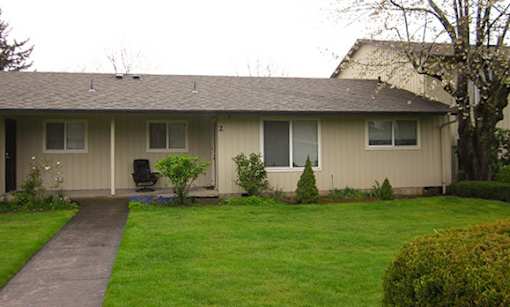 A house with a brown roof and a green lawn.