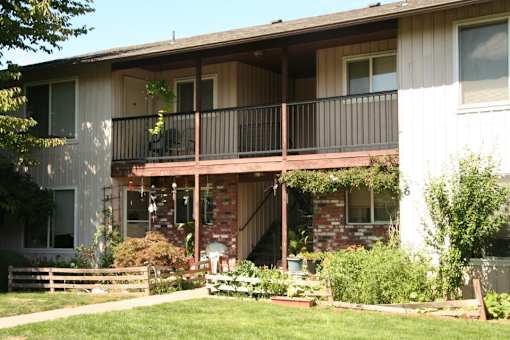 A house with a balcony and a garden in front.