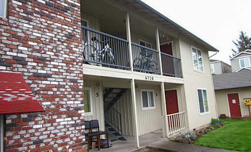 A red brick building with a balcony and a bicycle on it.