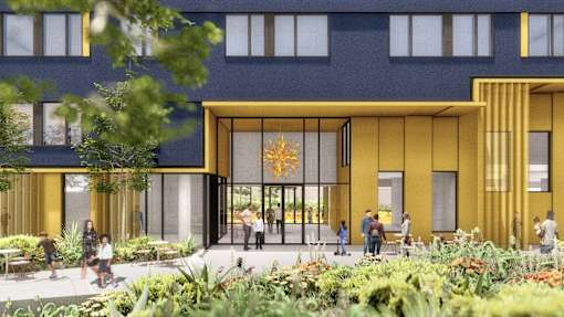 A modern building with a yellow entrance and people walking around.
