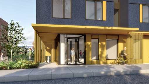 A modern building with a yellow entrance and people walking in.