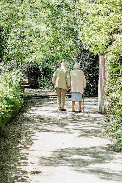 an elderly couple walking down a garden path