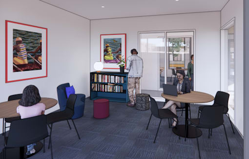 A woman is sitting at a table in a room with a bookshelf and a painting on the wall.
