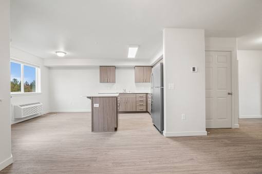 A kitchen area with a refrigerator, cabinets, and a countertop.