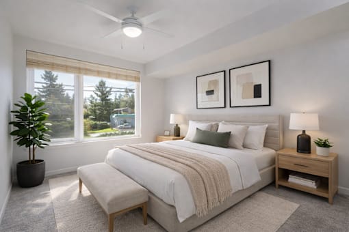 A bedroom with a large bed, a potted plant, and two framed pictures on the wall.