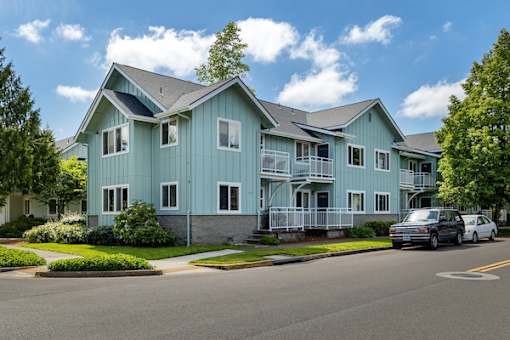 A blue two-story house with a car parked in front.