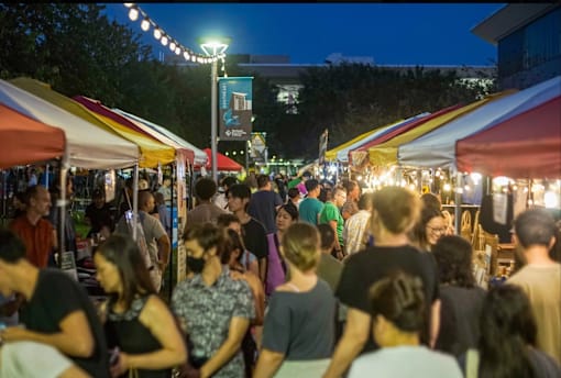 A busy night market with people walking and shopping.