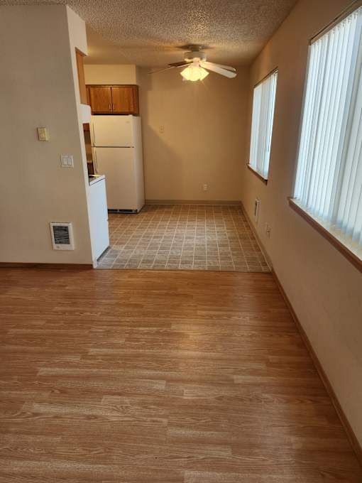 A kitchen with a refrigerator and a ceiling fan.