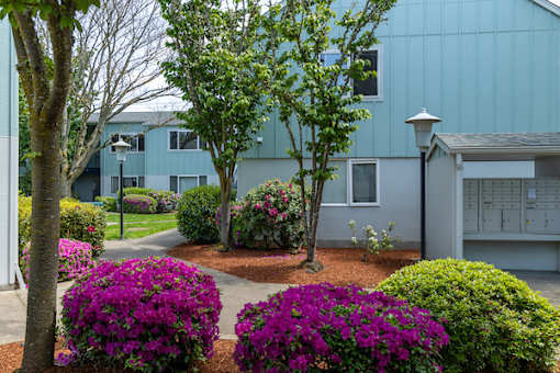 A blue building with a white garage door and a tree in front.
