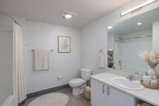 A bathroom with a toilet, sink, and mirror.