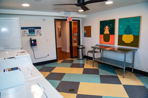 a laundry room with a checkered floor and a refrigerator and a table