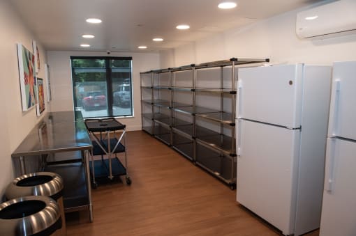 an empty room with two refrigerators and a table and chairs