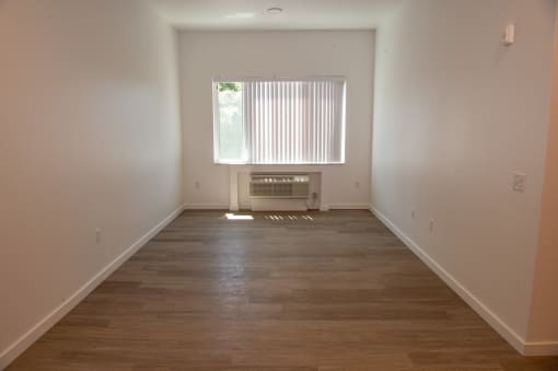 an empty room with wooden floors and a window