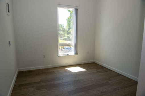an empty room with a window and wooden floors