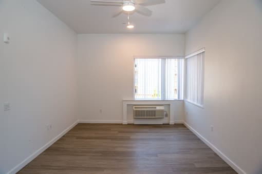 an empty living room with a ceiling fan and a window
