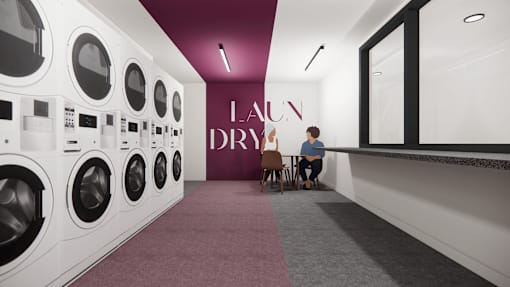 A person is sitting on a chair in front of a row of washing machines.