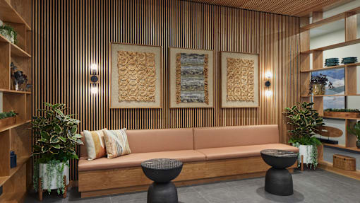 A living room with a couch, two tables, and a wooden wall.