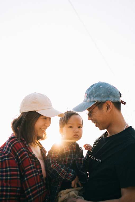 A family of three wearing hats and casual clothing are standing together.