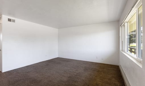A room with white walls and brown carpet.
