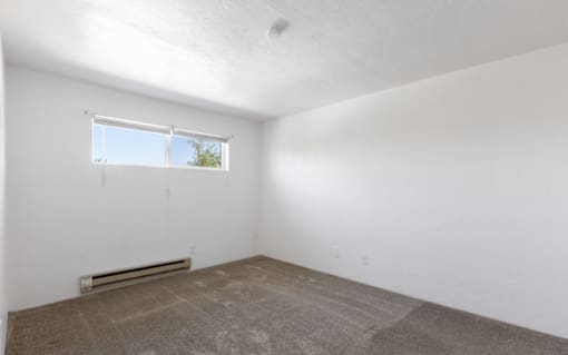 A room with a window and a heater on the floor.