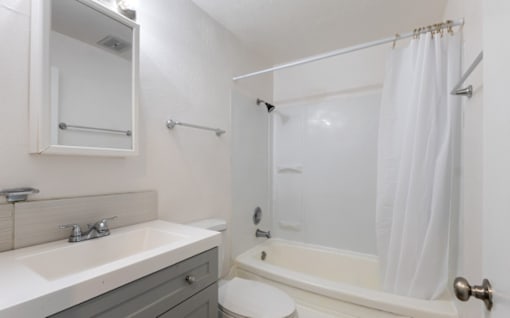 A white bathroom with a toilet, sink, and bathtub.
