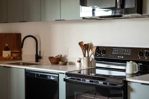A modern kitchen with a black oven and a black faucet.