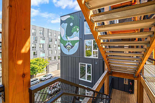 A wooden staircase leads to a balcony with a mural of a bear on the side of a building.