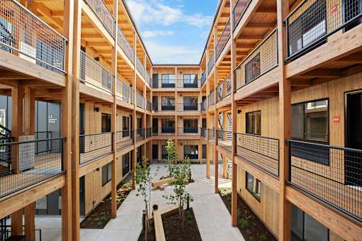 A courtyard surrounded by balconies with a tree in the center.