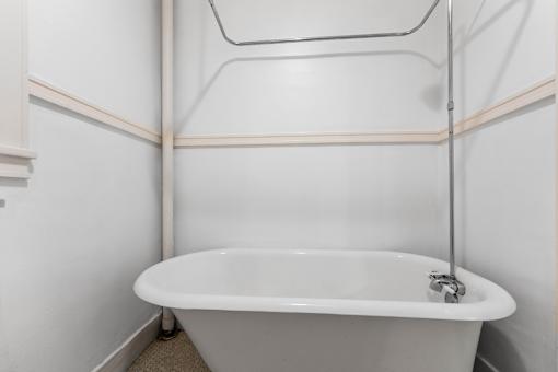 A white bathtub with a shower head attached to the wall.