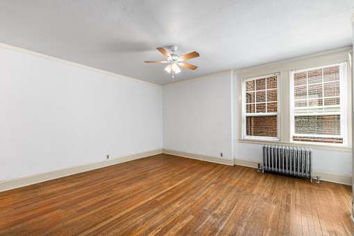 A room with a ceiling fan and a window with blinds.