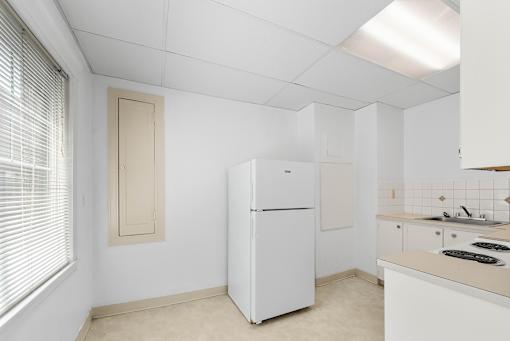 A white kitchen with a fridge and a window.