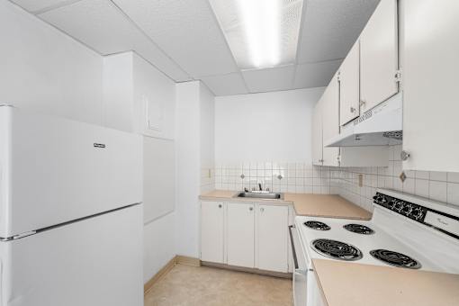 A white kitchen with a refrigerator, stove, and cabinets.