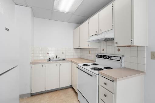A white kitchen with a stove top oven and a sink.