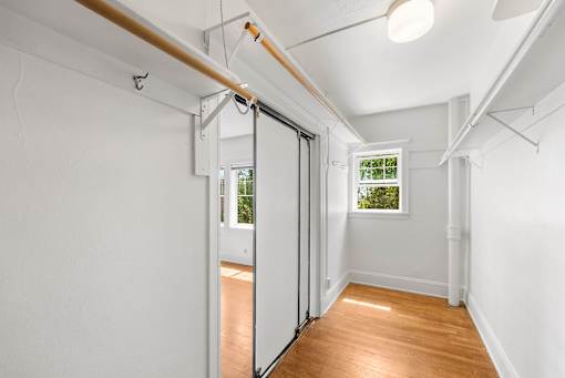 A room with white walls and wooden flooring with a sliding door.