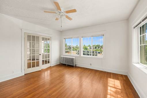 A room with a ceiling fan and a window with a view of trees.