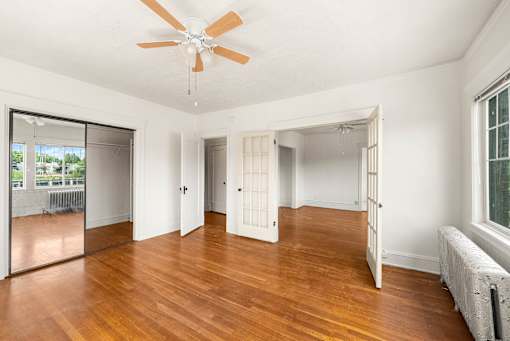 A room with a ceiling fan and wooden floors.