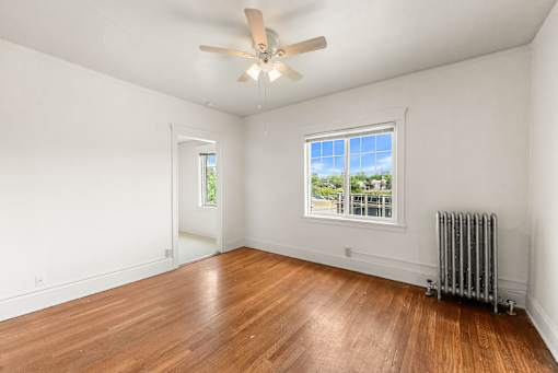 A room with a ceiling fan and a window with a view of the outside.