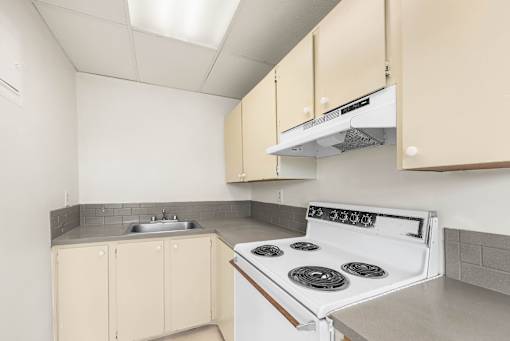 A kitchen with a white stove and beige cabinets.